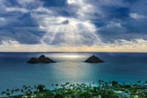 雲の合間から光が差し込む岩のある綺麗な海